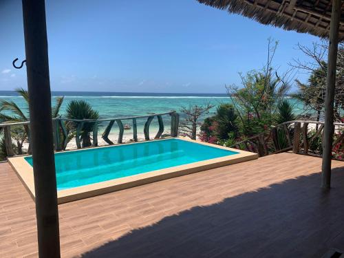 a swimming pool with the ocean in the background at Zi Villa Beach Cottage in Matemwe