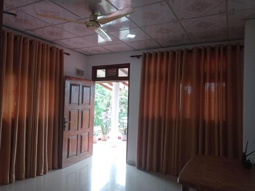 una habitación vacía con cortinas naranjas y una puerta en Weligama Elite Guest, en Weligama