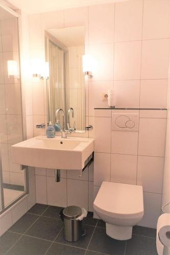 a white bathroom with a sink and a toilet at Mählich Haus in Manderscheid