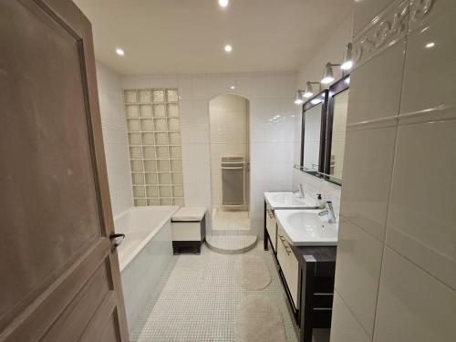 a white bathroom with a tub and a sink at Blaise 4 pieces in Saint-Étienne-de-Tinée