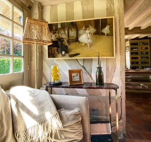 una sala de estar con sofá y una pintura en la pared en L’Agapé : Le charme absolu de la Normandie, en Saint-Pierre-Azif