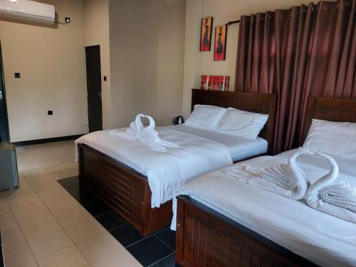 two beds in a hotel room with towels on them at Edwin's Airport Garden in Negombo