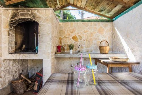 uma cozinha em pedra com uma mesa e um lavatório em Apartment Dragica (A2), Pašman em Pasman