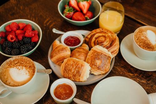 a table topped with plates of pastries and bowls of fruit at Pennyhill Park Hotel and Spa in Bagshot