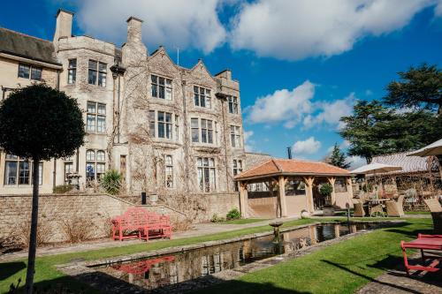 an old stone building with a pond in front of it at Pennyhill Park Hotel and Spa in Bagshot