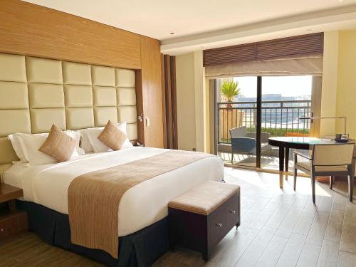 a hotel room with a large bed and a balcony at Sofitel Al Khobar The Corniche in Al Khobar
