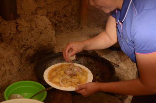 Shatyly Lake ViewGlamping في Bokonbayevo: امرأة تطبخ طبق من الطعام في wok