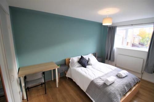 um quarto com uma cama, uma secretária e uma parede azul em St James House - Charming 3 bed, 2 bathrooms, driveway parking, close to town centre em Newcastle upon Tyne