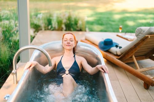 a woman is sitting in a hot tub at Pennyhill Park Hotel and Spa in Bagshot