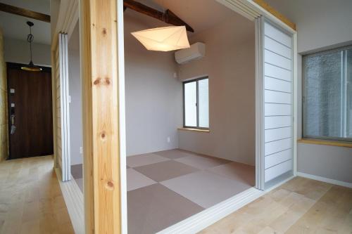 a hallway with a door leading into a room with white walls at Etcetera Guest House in Niijimamura