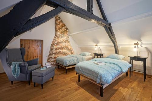 a bedroom with a bed and a chair in a room at La Ferme du Parc - Gite Le Fournil in Montignies-lez-Lens