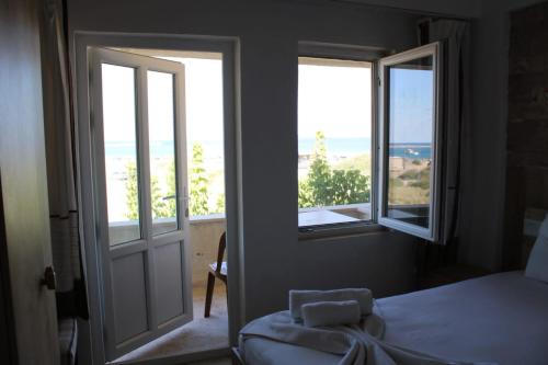 a bedroom with two windows and a bed with a chair at GÖKÇEADA BATIHAN OTEL in Bademli