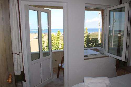a room with a door and a view of the ocean at GÖKÇEADA BATIHAN OTEL in Bademli