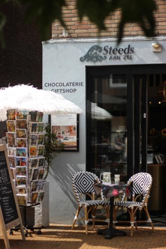 two chairs and an umbrella outside of a store at Hotel Steeds aan Zee in Katwijk