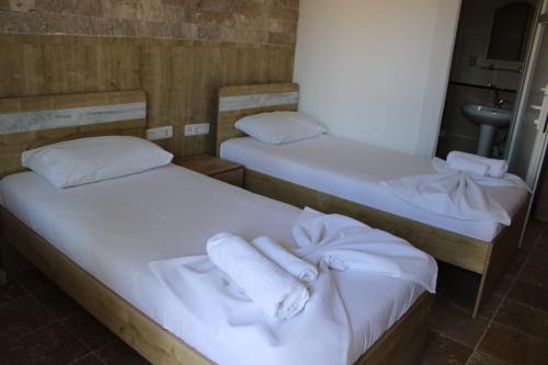 two beds in a room with white towels on them at GÖKÇEADA BATIHAN OTEL in Bademli
