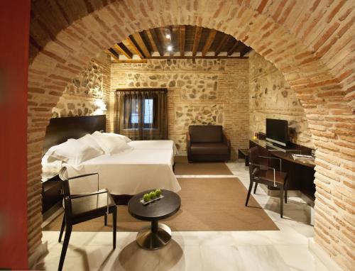 a room with a bed and a desk and chairs at Pintor El Greco in Toledo