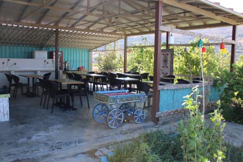 a covered patio with tables and chairs and a cart at GÖKÇEADA BATIHAN OTEL in Bademli