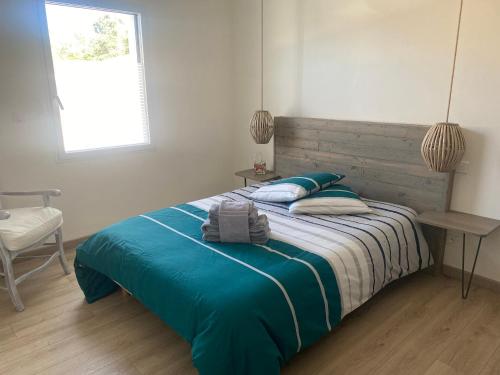- une chambre avec un lit doté de draps bleus et une fenêtre dans l'établissement Maison en bord de mer au Domaine du Bois Soret, à Notre-Dame-de-Monts