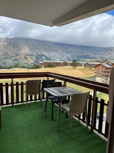 una mesa y sillas en un balcón con vistas en Appartement SUPERDEVOLUY en Le Dévoluy