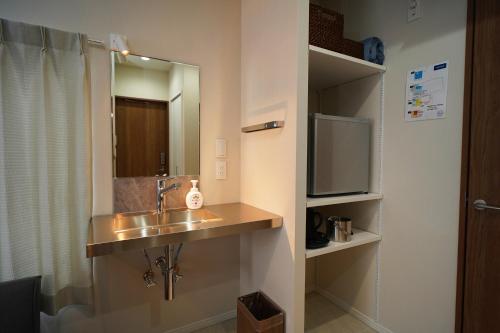 a bathroom with a sink and a mirror at Etcetera Guest House in Niijimamura