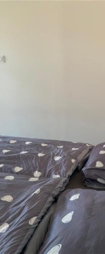 a bed with a blanket with white spots on it at Apartamenty Bezrzecze in Szczecin