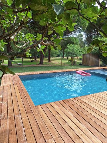 une piscine avec une terrasse en bois et un frisbee rouge dans l'établissement La Pinède du Chéou, Piscine, Logement indépendant, Parking, Draps, Wifi fibre, à Mimizan