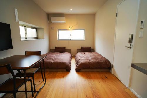 a room with two beds and a table and a desk at Etcetera Guest House in Niijimamura