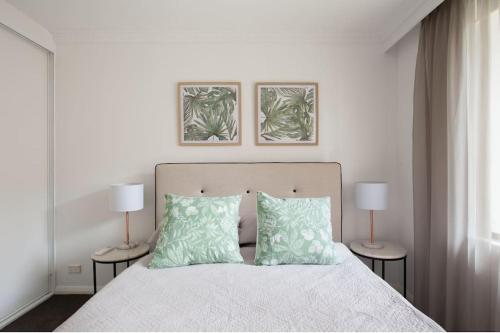 1 dormitorio con 1 cama con almohadas verdes y 2 lámparas en Harbourside Style, 2 Bed, A/C, Pool -Elizabeth Bay en Sídney