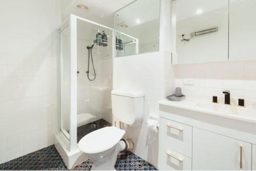 Baño blanco con aseo y lavamanos en Harbourside Style, 2 Bed, A/C, Pool -Elizabeth Bay en Sídney