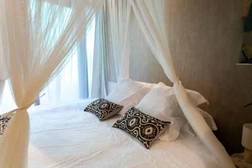 1 cama blanca con 2 almohadas y ventana en Bali Serenity Balnéo et lit rond, en Lagnieu