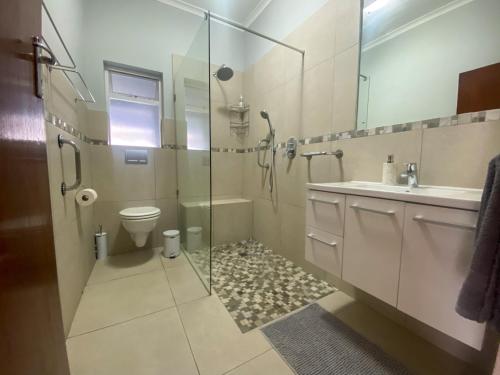 a bathroom with a shower and a toilet and a sink at Crescent Corner Vacation Home in Cape Town