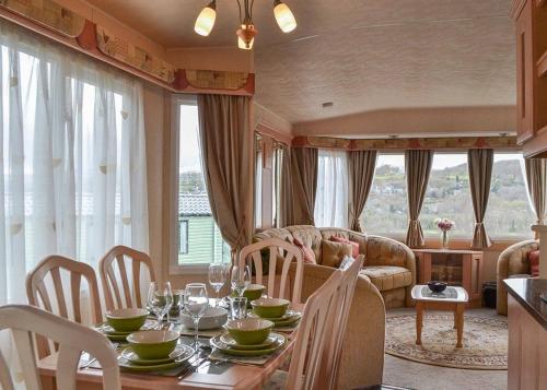 a dining room with a table and chairs and a couch at Tan-y-fron Holiday Park in Dolgellau