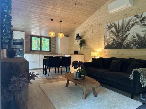 uma sala de estar e cozinha com um sofá e uma mesa em Le chalet du lys avec bain scandinave Insolys em Gouvieux