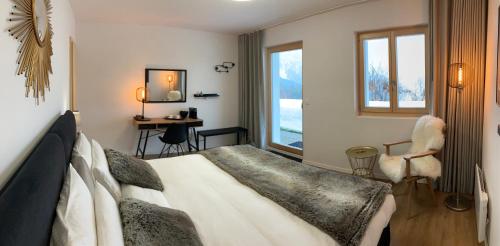 1 dormitorio con cama, escritorio y ventana en Le Lézard et la Grenouille BnB, en Ovronnaz