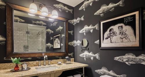 a bathroom with a sink and a mirror and fishes on the wall at Graduate Minneapolis in Minneapolis