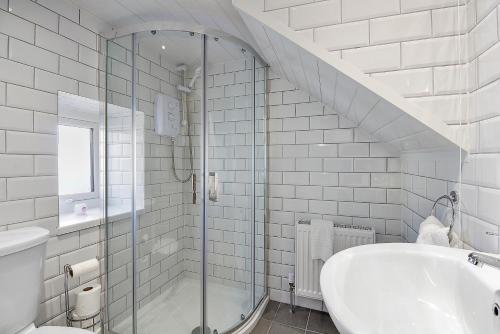 a white bathroom with a shower and a sink at The Wee House in Muff