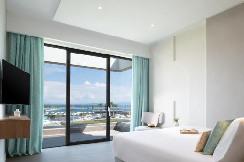 a hotel room with a bed and a large window at Miraggio Thermal Spa Resort in Paliouri