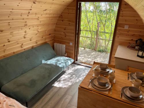 um quarto com um sofá e uma mesa num quarto em Wind In The Willows Luxury Glamping em Peterborough