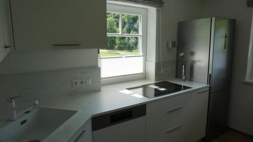 a white kitchen with a refrigerator and a window at Apartment Bachweg in Forstau