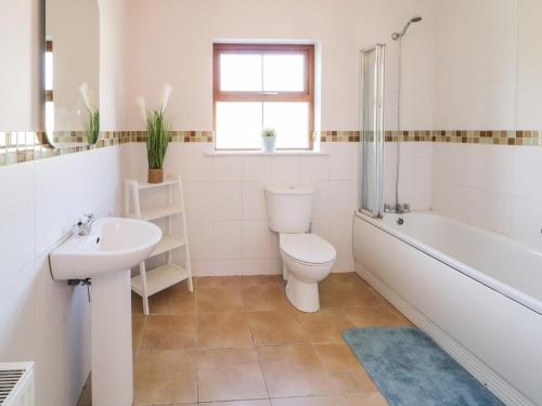 a bathroom with a toilet and a tub and a sink at Owen Tucker View House in Ardara