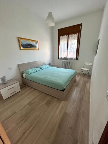 een slaapkamer met een bed en een houten vloer bij Sunflowers house in Punta Marina