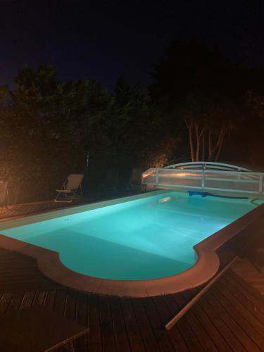 een blauw zwembad 's nachts met een terras bij Chambre d'hôtes Maison des 5 Fleurs in Heugas