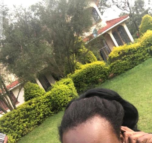 a woman is standing in front of a house at Elegant all ensuite 4 bedroom with beautiful large garden for events in Kakamega