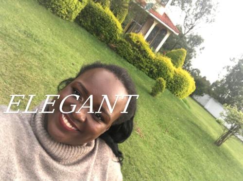 Una donna in piedi davanti a un cortile con la parola "elemento" di Elegant all ensuite 4 bedroom with beautiful large garden for events a Kakamega