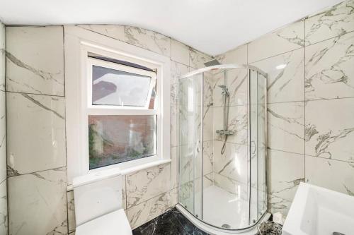 a bathroom with a shower and a window at A Stunning 3Bed house with WiFi in Chatham