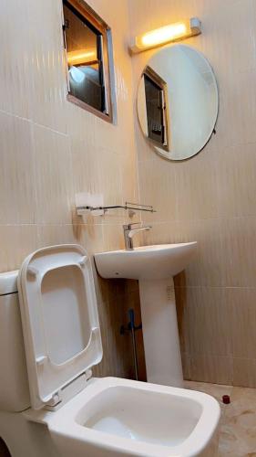 a bathroom with a toilet and a sink and a mirror at Residence Meublée Liberté 2 in Dakar