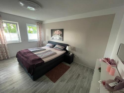 een slaapkamer met een bed en 2 ramen bij Karins Kotte in Papenburg
