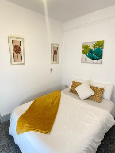 a bedroom with a white bed with a yellow blanket on it at SEV Apartments Wakefield in Hemsworth