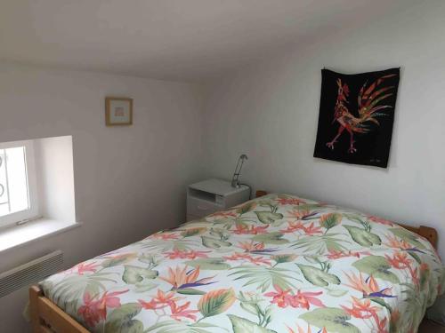 a bedroom with a bed with a floral comforter at Classé 2 étoiles - 3 chambres - Appartement Douillet au bord du Quai De Londres dans le cœur de la ville de VERDUN - Géré par Presta-Zen'Services in Verdun