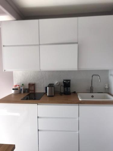 une cuisine avec des armoires blanches et un évier dans l'établissement Le nid sur la mer, à Deauville